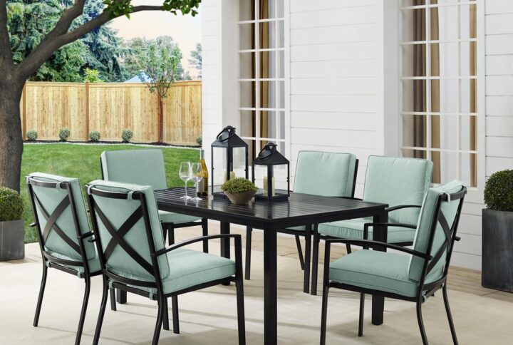 Gather around the Kaplan 7pc Outdoor Dining Set for an elegant meal al fresco. The rectangle table features a slatted design that elevates the sturdy steel construction and creates a perfect partner to the six outdoor dining chairs. Each chair showcases comfy back and seat cushions plus a classic x-back design. The table has a standard umbrella hole that will allow you to add some shade on a hot summer day. Simple and stunning