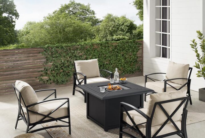 Gather for an evening around the fire with the Kaplan 5pc Outdoor Conversation Set. Four arm chairs surround the propane-powered fire table providing cozy outdoor seating. The chairs have comfortable seat and back cushions covered with solution-dyed polyester. With a slatted top and solid paneled base