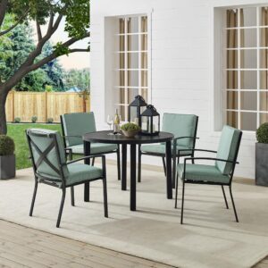 Gather around the Kaplan 5pc Round Dining Set for a cozy meal al fresco. The round table features a slatted design that elevates the sturdy steel construction creating a perfect partner to the four outdoor dining chairs. Each chair showcases comfy back and seat cushions plus a classic x-back design. The table has a standard umbrella hole that will allow you to add some shade on a hot summer day. Simple and stunning