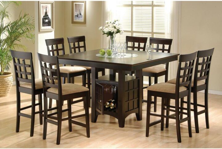 This nine-piece counter height table set comes complete with a spacious square table and eight windowpane style chairs in a deep cappuccino finish. The elegant table features a storage pedestal base that holds wine glasses as well as bottles
