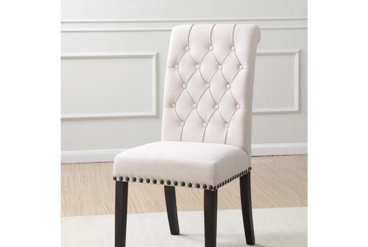 Stick with a stylish elegant impact. An extra high back dominates the alluring silhouette of this dining chair. Fresh beige linen upholstery stylizes and brightens any space. Charming tufting on its seat back and nailhead trim supplies plenty of accenting. Tasteful smokey black finish legs offer slight curves in back.