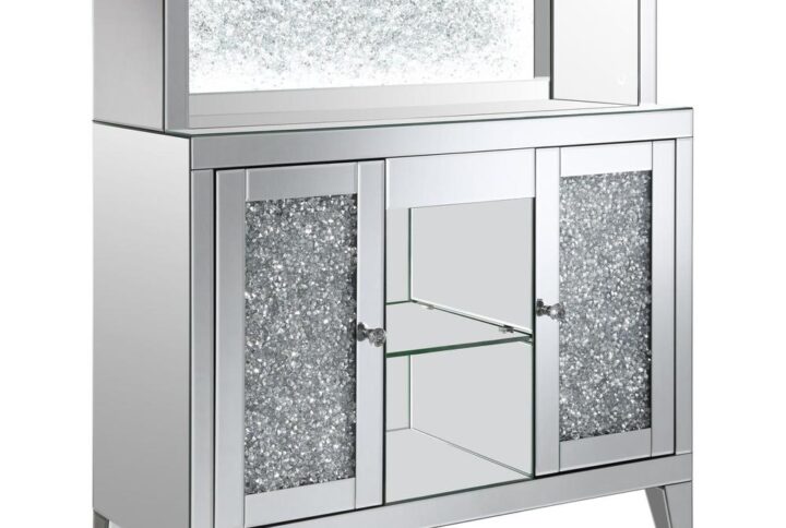 This wine cabinet is a striking statement piece that features a highly reflective surface made of mirror tiles and trim. The faux diamond encrusted doors and crystal knobs add a hint of sparkle while the open back shelf emits a soothing glow. This spacious rectangular frame is perfect for creating a dramatic effect on any focal wall.