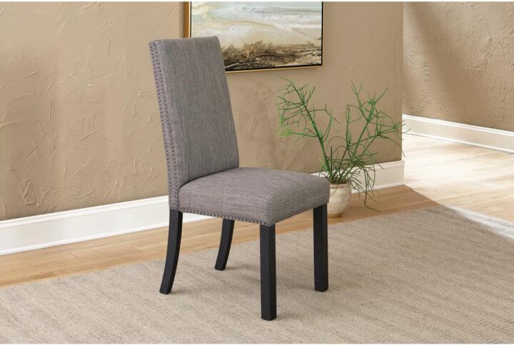 Stylish parson dining chair features organic materials and details. Chair is crafted from Asian hardwood in a modern industrial design. The webbed seating offers comfort while the hand applied nail head trim and double stitched seams convey stylishness. Matte black legs and cool charcoal grey fabric upholstery create a warm two-tone look. This dining chair is a charming stylish addition to a transitional dining space.