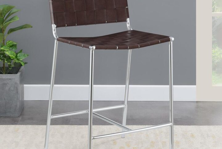 Mid-century elements lead the design aesthetic of this contemporary stool. A slim metal frame in a gleaming chrome finish offers a striking contrast against the brown faux leather accents. Narrow leatherette bands weave together to create a backrest and seat