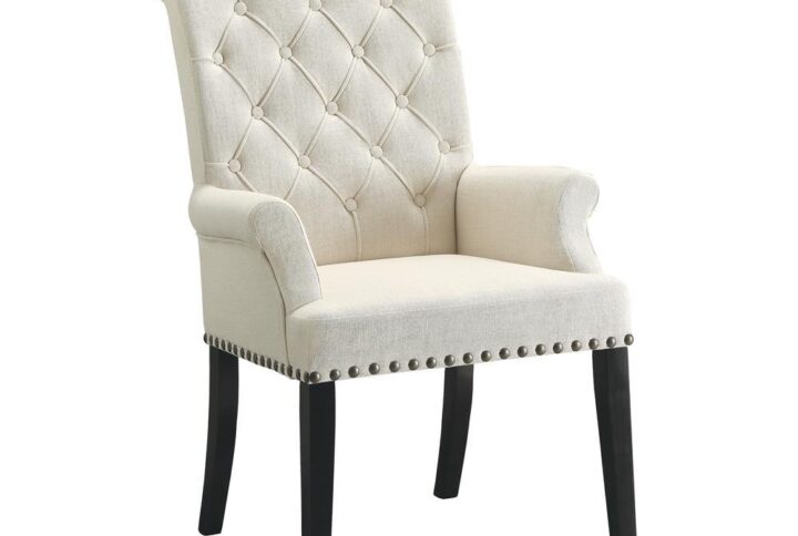 Seat guests in ultimate comfort. This dining arm chair represents an artful upgrade to modernize a casual space while preserving traditional charm. Lovely beige upholstery infuses light and a fresh ambiance. Button tufting on its seat back joins sleek nailhead trim to add captivating accents. Dark finished legs provide the perfect contrast to complete a fabulous design package.