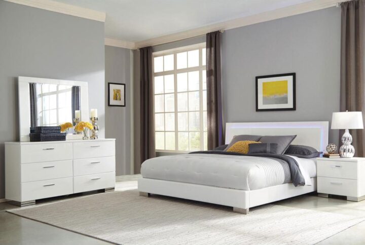 Update the master bedroom with this contemporary 4-piece bedroom set from the Felicity collection. The exquisite bed features a very low footboard and futuristic headboard with blue LED touch lighting. The nightstand and dresser have deep drawers accentuated by lustrous polished chrome metal handles and felt-lined top drawers. Rounding out the set is a rectangular mirror that easily fits atop the dresser. The entire set is brilliantly finished with a stunning white polyurethane coat polished to a high-gloss finish for a modern appeal that's sure to please.