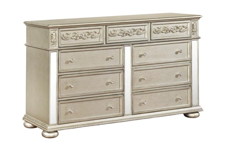 Add luxurious style to your bedroom with this glam dresser. This nine drawer dresser displays a metallic platinum finish for a luxurious touch. The mirrored panels provide added visual punch in this luxe dresser. Three slim top drawers are anchored by six additional larger drawers for ample organizing space. Traditional wood carved details on the top drawer fronts provide additional visual interest for an overall glamorous look.