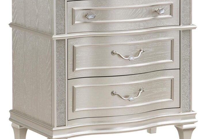 Keep all your bedroom essentials and wardrobe items neatly organized with this glam three-drawer nightstand. A contoured frame design features sparkling side panels flanking the three spacious drawers for a luxurious touch. A silver oak finished wood frame is accented further by modern glam metal knobs and bail handles that help slide each drawer with ease. A soft grey felt-lined top drawer invites you to store more delicate items. A hidden USB outlet creates a convenient charging area for handheld devices.