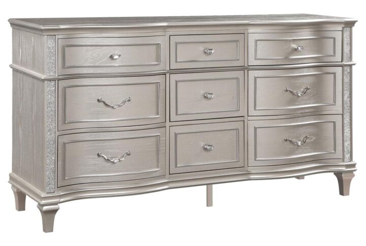 A silver oak finish creates an elegant touch to this glam nine-drawer dresser. Hexagon-shaped knobs and drop bail handles appointed with pearl accents adorn each of the nine spacious drawers for a luxurious look and feel. Keep delicate essentials organized within the grey felt-lined top drawers and garments in the deep bottom drawers. Across the dresser front is a curved facade that sweeps through the drawer fronts and ends at two sparkling column panels. Charming wood molding details along the top and bottom