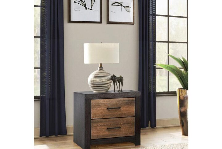 Don't be surprised if you instantly fall for this transitional two-drawer nightstand with a rustic two-tone twist. It casts a warm aura that evokes Nature with reclaimed wood materials construction. The nightstand comes in a deep licorice finish that soothes the senses. Each drawer features a caramel finish with wood grain details and is adorned with a richly hued dark bronze metal pull handle. Solid legs and sides give it optimal stability and durability.
