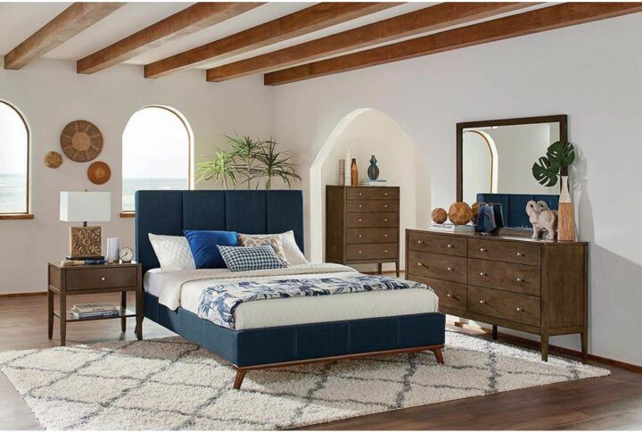 The Charity collection presents this attractive bed with a smooth silhouette. It features a high headboard and low-profile footboard with a paneled design. The bed is wrapped in a blue upholstery for added distinction. The angled legs add a modern