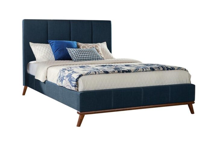 The Charity collection presents this attractive bed with a smooth silhouette. It features a high headboard and low-profile footboard with a paneled design. The bed is wrapped in a blue upholstery for added distinction. The angled legs add a modern