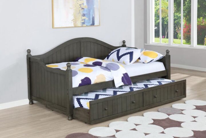 Expand the sleeping space in your home with this transitional twin size daybed.It's crafted with a pull-out trundle that will lend practicality and comfort to any room.The bed features an arched back and sloped arms with a paneled headboard in a warm grey finish.The matching trundle comes with convenient round knobs in the same warm grey hue.This handsome space-saver will help invoke the vibe of a cozy home throughout.