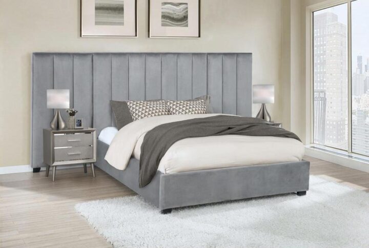 Contemporary and edgy style takes on a plush quality with upholstery fit for a comfy master or guest suite as this modern bed with side panels anchors a haven for ultimate relaxation. Add dimension and cool color to any bedroom with this platform bed and wrapped in cool gray velvet upholstery and embellished with two wide wall panels that dominate an integral wall. Vertical strips create geometric energy to wall panels backing a simply styled bed covered in gray velvet and sitting on petite black finish feet. A versatile yet timely palette invites surrounding case pieces tailored to personal taste. Set includes one bed and two wall panels.
