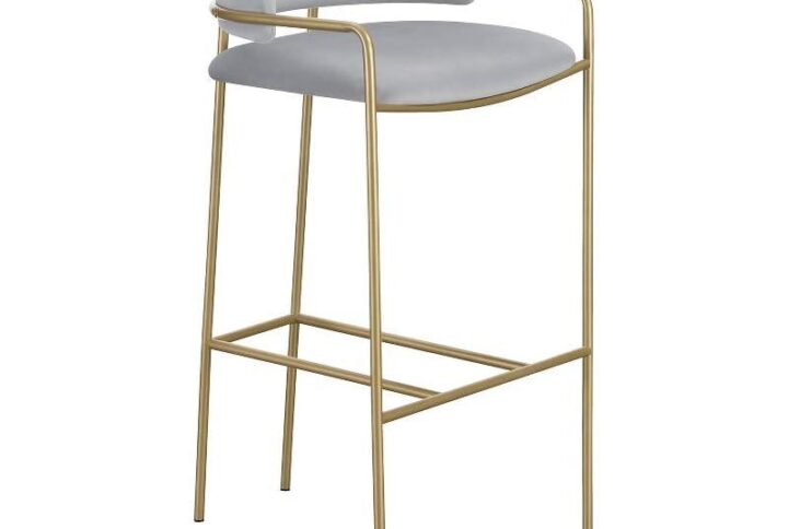 A soft and supple grey velvet envelops the comfy padded seat and linear backrest of this chic and glamorous stool. Situated and supported by a slim rod-like frame in a gold finish