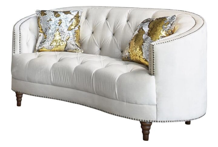 This modern spin on a classic loveseat will transform your living space. It features a cozy C-shape design that's innovative and graceful. The soft champagne velvet upholstery radiates with a chic energy and features the glam of deep rhinestone button tufting. Chrome nailhead trim throughout adds a subtle elegance that can't be ignored. Exquisitely turned legs and included complementary accent pillows complete the design of this magnificent loveseat.