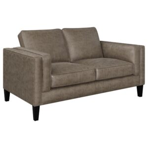 featuring a tailored tuxedo style frame with double track arms upholstered in a neutral vintage brown leatherette. Plush box seat and back cushions with self-welt trimmed edges offer a finishing touch