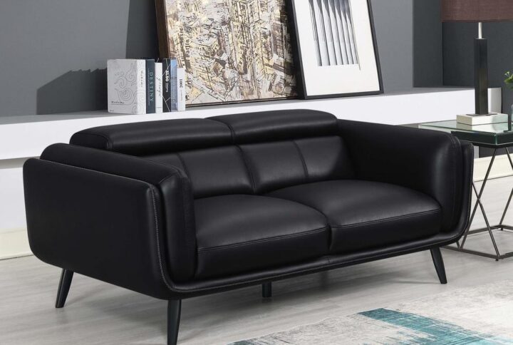 Transform your compact living room with this striking tuxedo-inspired modern loveseat. Upholstered in a smooth black leatherette across its mid-century modern silhouette