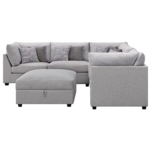 it shows off on-trend gray fabric upholstery and complementary patterned accent pillows that add dimension. The set includes a storage ottoman