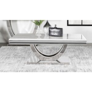 Transform your contemporary living room seating area with this modern glam coffee table. A large rectangle shaped top made of white engineered stone lends a timeless aesthetic with its marble-like resemblance. Two slender curved bars create a demilune shaped pedestal base that grounds the table and offers a sleek ultra-modern look and feel. Across the base is a gleaming polished chrome finish