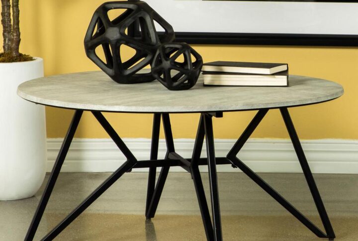 Gunmetal finish hairpin legs offer an industrial edginess to this modern coffee table. Designed with a faux cement top in an elegant round shape