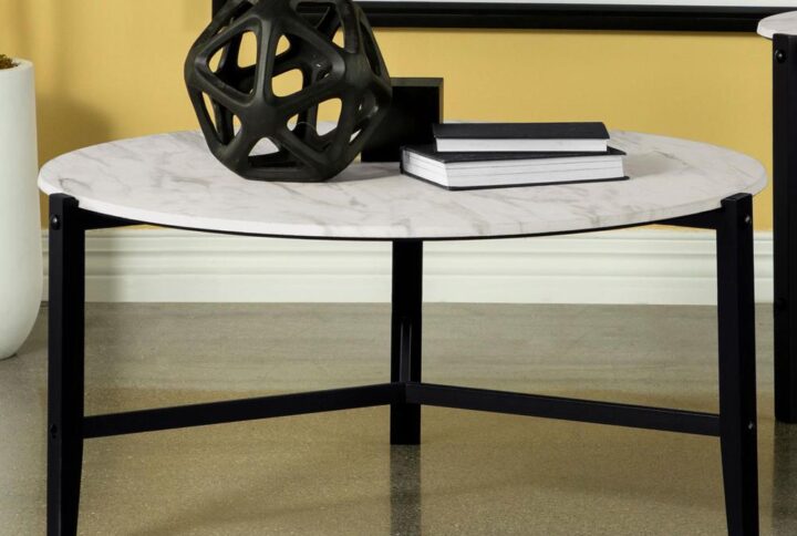Create a minimal aesthetic in your living room with this modern coffee table. Slim black metal legs come together to create a stand-like base that floats a spacious round tabletop. The round tabletop offers a faux white marble-inspired design with a textured feel