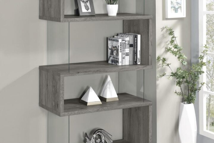 The asymmetrical zig-zag design of this contemporary bookcase creates a focal point in any room. Five open shelves in a light grey driftwood finish stack elegantly