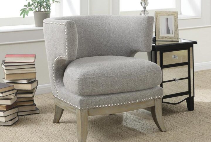 This distinctive accent armchair is designed to stand out in any room of the home. It's built with a barrel back and high armrests that look impressive. Stylishly decorated with nailhead trim along the frame and side cutout beneath the armrests. Flared legs are finished in a weathered grey. It's wrapped in cool grey chenille that suits any living room or entertainment room decor.