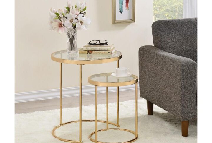 Include this sleek and sophisticated set of two nesting tables in your decor. A gold gauge steel frame makes a charming display for both pieces. The round tabletops allow you to conveniently place beverages and small items within reach. Their simplistic design ensures they beautifully blend with your decor while serving as a functional upgrade. Choose this set of two gold and glass nesting tables for your modern decor.