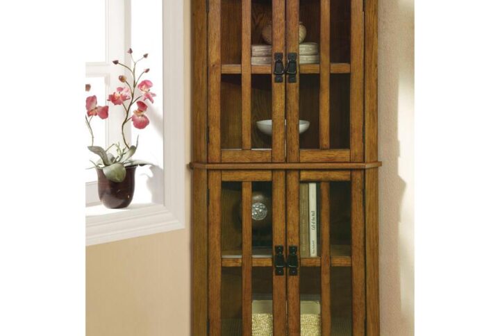 This curio cabinet is a magnificent addition to the home. It's designed to fit seamlessly in the corner of the living room or bedroom. It's crafted with four doors with window panels that has an enduring appeal. Each door opens to a space that's divided into two storage areas with plenty of room for decorative plates or vases as well as knickknacks and a book collection. It is finished in a sumptuous golden brown that will be a highlight of any room it's in.