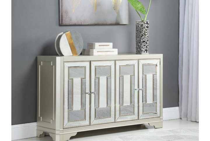 A glam style accent table is a treat for any eye to meet. Four cabinet doors make this a roomy and spacious essential for storing items. Take note of the gorgeous crystal-like round knobs. The accent table's champagne finish and mirrored cabinet panels will immediately accent your decor. Bracket style legs add to its aesthetic appeal while providing support.