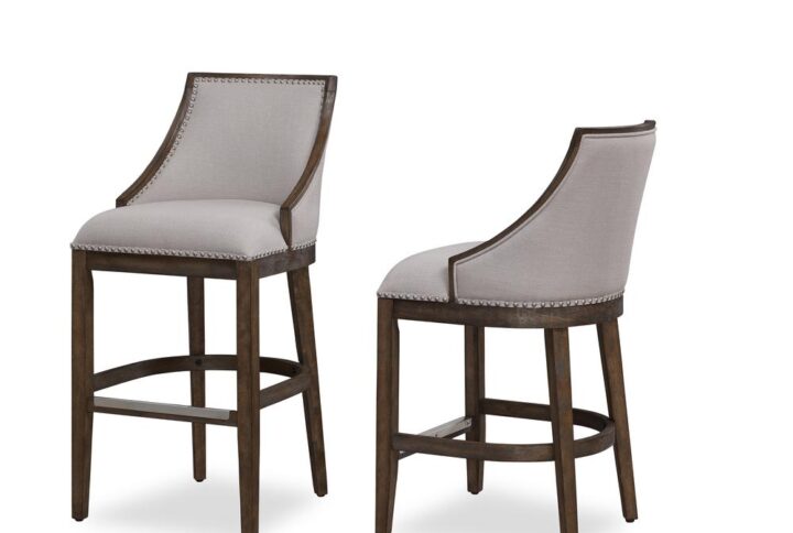 Defined by gracefully swooped arms and brushed nickel nailhead trim the Gilford bar stool will be an elegant addition to your kitchen or bar. The solid hardwood frame is finished in driftwood brown and accented by beautiful beige fabric on the seat and back. Sturdy tapered legs and a four-sided stretcher provide strength and a comfortable footrest protected by a metal kickplate.