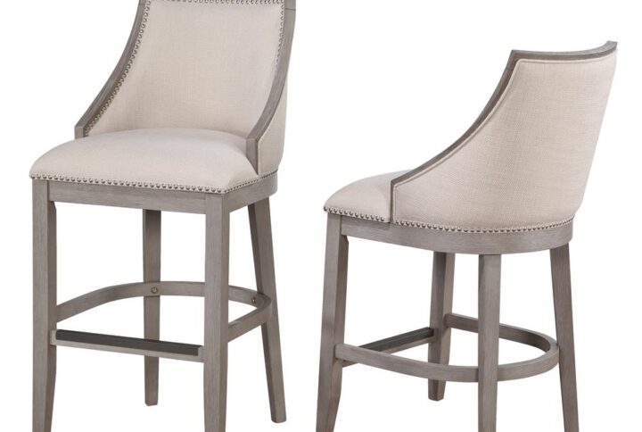 The Paighton Counter Stool with gracefully swooped arms and brushed nickel nail head trim will be an elegant addition to your kitchen or bar. The solid hardwood frame is finished in driftwood grey and accented by the stylish linen-look fabric on the seat and back. Sturdy tapered legs and a four-sided stretcher provide strength and the comfortable footrest is protected by a metal kickplate.