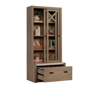 The bookcase with sliding doors from the Dixon City collection has a rustic farmhouse appeal coupled with a touch of contemporary style. Finished in the natural tone of Brushed Oak with Pebbled White accent