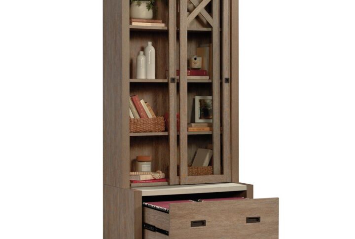 The bookcase with sliding doors from the Dixon City collection has a rustic farmhouse appeal coupled with a touch of contemporary style. Finished in the natural tone of Brushed Oak with Pebbled White accent