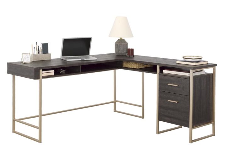 This modern L-shaped desk from the Walter Heights™ collection is a must-have for anyone looking to create a stylish and functional home office. The Blade Walnut™ finish paired with the powder-coated metal frame in an elegant champagne gold finish adds a touch of sophistication to this L-shaped desk. The spacious work surface of this home office desk provides ample room for multiple monitors