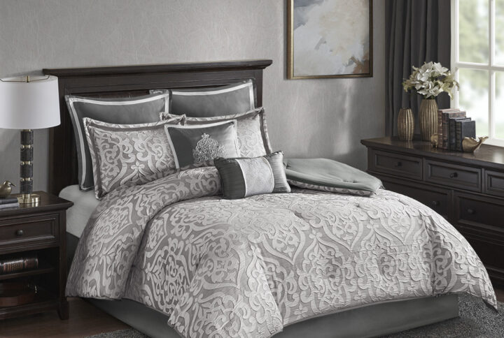 Add a touch of class to your bedroom with the Madison Park Odette 8 Piece Jacquard Comforter Set. The luxurious textured jacquard comforter and shams flaunt a gorgeous damask medallion design with silver striations on the satin ground that add dimension to the lavish look. A solid grey reverse and stunning Euro shams complement the top of the bed to complete the ensemble. Also included are two decorative pillows that feature embroidery and cording details