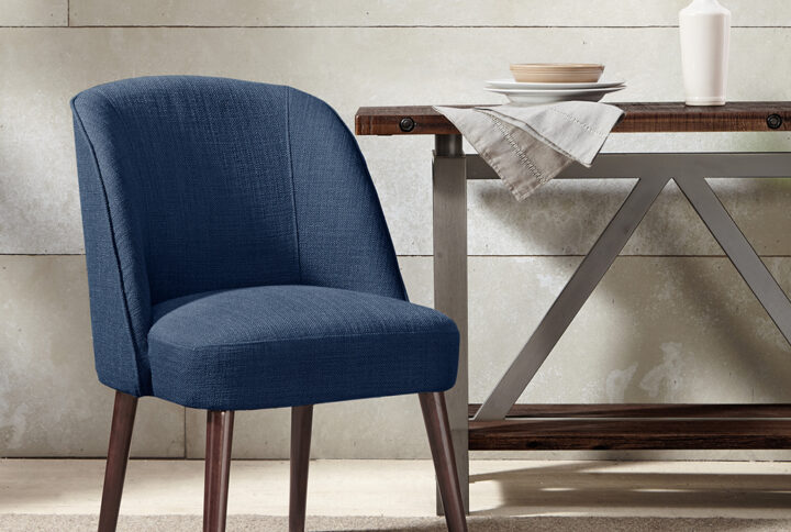 The soft curves of the wraparound back of this dining chair highlight the thin tapered legs