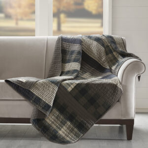 The Woolrich Winter Plains quilted throw features plaid pieced stripes in shades of brown and tan and reverses to a solid brown color. Made from 100% cotton