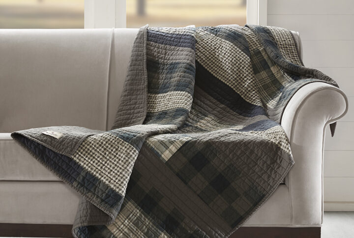 The Woolrich Winter Plains quilted throw features plaid pieced stripes in shades of brown and tan and reverses to a solid brown color. Made from 100% cotton