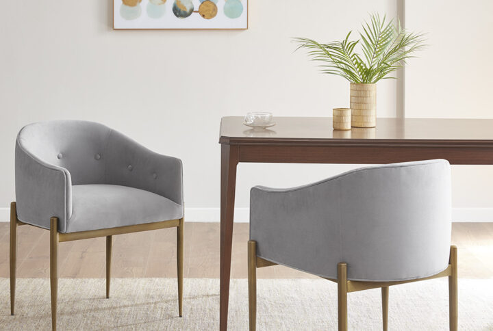 Bring glamorous style to your dining room with the Madison Park Sheraton Dining Chair Set of 2. Each dining chair is upholstered in a soft grey fabric with tufted buttons around the arms and low back to create a luxurious modern look. The metal legs flaunt a distressed gold finish to complement the upholstery and give the chair an upscale