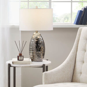 this table lamp flaunts an eye-catching silver finish to create a luxurious transitional look. The white drum shade complements the lustrous look and softly filters the light to give your living room or bedroom a welcoming warm glow. Elevate any room in your home by incorporating this gorgeous table lamp into your space. 1 Type A bulb is needed (not included)