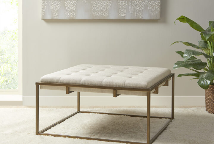 Elevate your living room décor with the elegance of the Madison Park Greenwich Ottoman/Coffee Table. This square ottoman is upholstered in a rich ivory fabric and features a tufted top that adds a sophisticated touch to the modern look. An antique bronze finish on the metal frame beautifully contrasts the upholstery