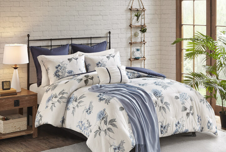 The Madison Park Zennia 7 Piece Printed Seersucker Comforter Set with Throw Blanket offers a charming farmhouse update for your bedroom. The textured seersucker comforter features an all-over floral print in soft blue and green hues on the white base