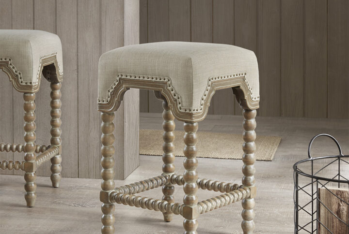 Bring an elegant farmhouse touch to your home with the Madison Park Christine Counter Stool. This square counter stool is upholstered in beautiful light grey fabric that features a bronze nail head trim for a rich accent. The solid wood turned legs and footrest displays a reclaimed grey wood finish to create a stunning transitional look. Accent your dining decor with this counter stool to complement your space with an elegant farmhouse allure. Assembly is required.