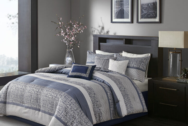 Give your bedroom a new luxurious look with the Madison Park Rhapsody 7 Piece Jacquard Comforter Set. This jacquard comforter features a navy and grey stripe design of several different motifs on the face with a solid grey reverse