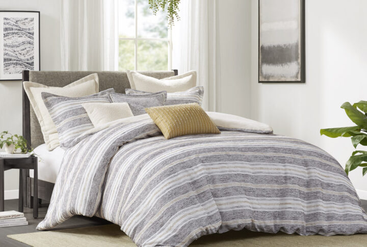 The Madison Park Signature Oasis oversized duvet-style comforter features a chenille jacquard stripe design in charcoal