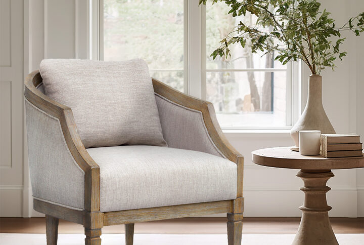 Introducing the Whitney Accent Chair from Martha Stewart's Bedford Collection. This armchair embodies classic sophistication and is the perfect addition to any room. Its wooden frame beautifully accentuates the graceful curvature of the back and scoop arms. Crafted with a solid wood frame in a reclaimed natural finish