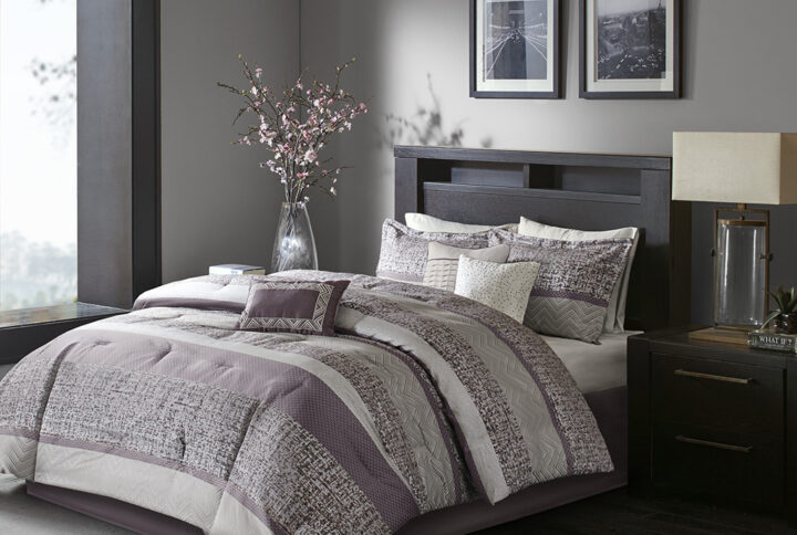 Give your bedroom a new luxurious look with the Madison Park Rhapsody 7 Piece Jacquard Comforter Set. This jacquard comforter features a purple and grey stripe design of several different motifs on the face with a solid beige reverse