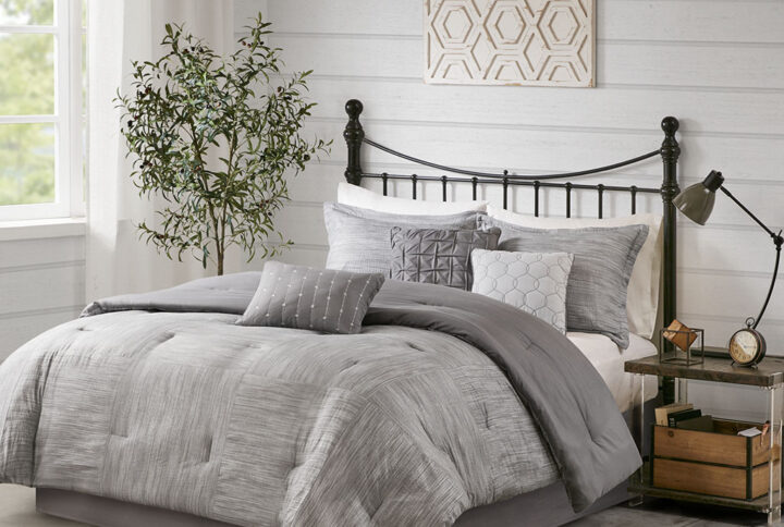 The Madison Park Walter 7 Piece Printed Seersucker Comforter Set offers a chic modern update to your bedroom. This grey comforter set features a pieced